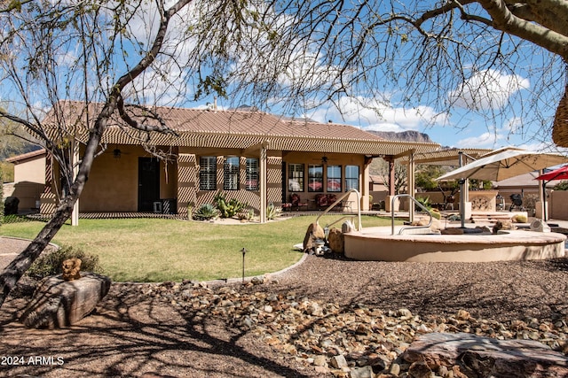 back of property featuring a patio area, stucco siding, a tiled roof, a lawn, and ceiling fan