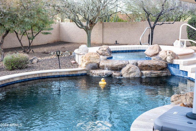 view of swimming pool featuring a fenced backyard and an in ground hot tub