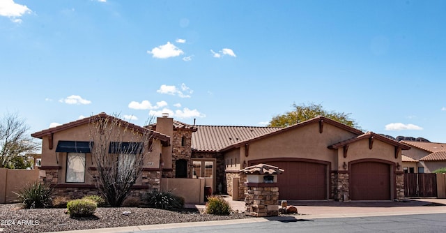 view of front of house with stone siding, a garage, fence, and a tiled roof