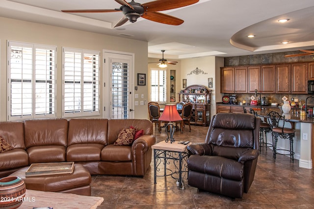 living area with a tray ceiling, ceiling fan, visible vents, and recessed lighting