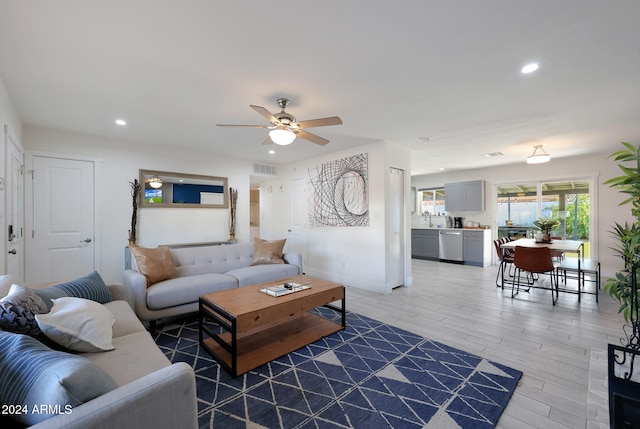 living room with wood-type flooring, ceiling fan, and sink