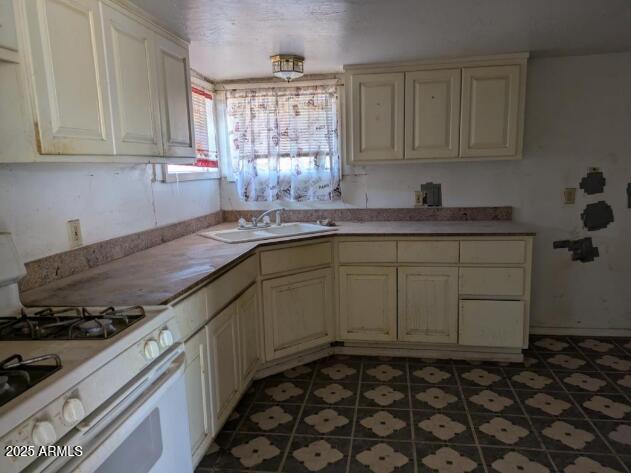 2602 E Jones Ave, Phoenix, AZ 85040 - kitchen featuring light tile patterned floors, white gas stove, cream cabinets, and a sink