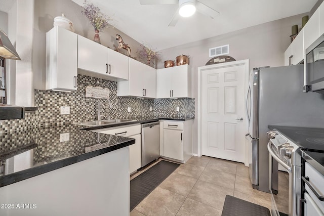 kitchen featuring stainless steel appliances, a sink, visible vents, tasteful backsplash, and dark countertops