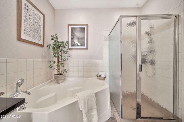 bathroom with tile walls, a garden tub, a shower stall, and vanity