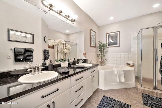 bathroom with a garden tub, a sink, a shower stall, and double vanity