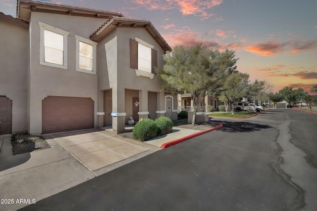 view of front of home featuring driveway, an attached garage, a tiled roof, and stucco siding