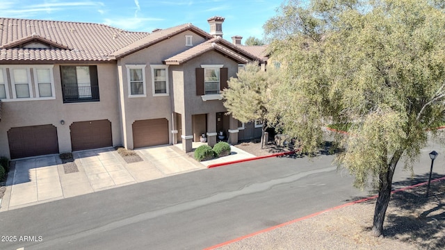 view of front of house with driveway, a tiled roof, an attached garage, and stucco siding