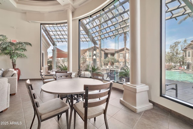 dining area featuring light tile patterned floors, decorative columns, and baseboards