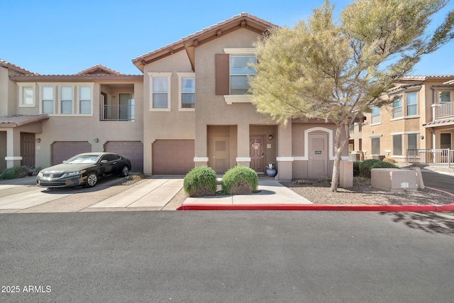 view of property with a tile roof, driveway, an attached garage, and stucco siding