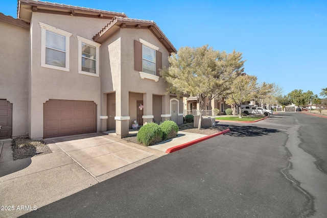 view of front of home featuring a garage, a tile roof, driveway, and stucco siding