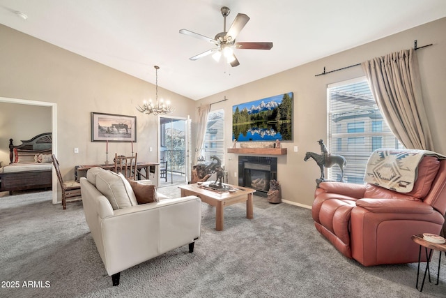 carpeted living room featuring lofted ceiling, ceiling fan with notable chandelier, a glass covered fireplace, and baseboards