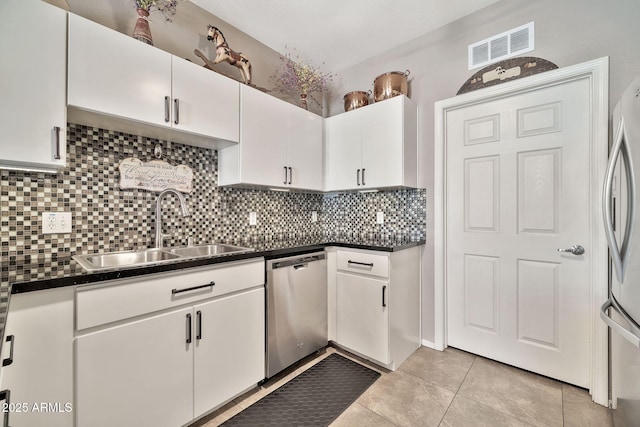 kitchen featuring stainless steel appliances, dark countertops, visible vents, and a sink