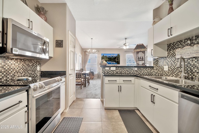 kitchen with dark countertops, backsplash, appliances with stainless steel finishes, a sink, and a peninsula