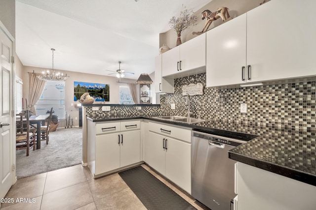 kitchen with dark countertops, backsplash, a sink, dishwasher, and a peninsula