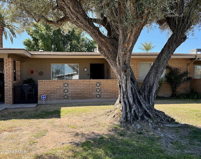 ranch-style home with brick siding, a front lawn, and fence