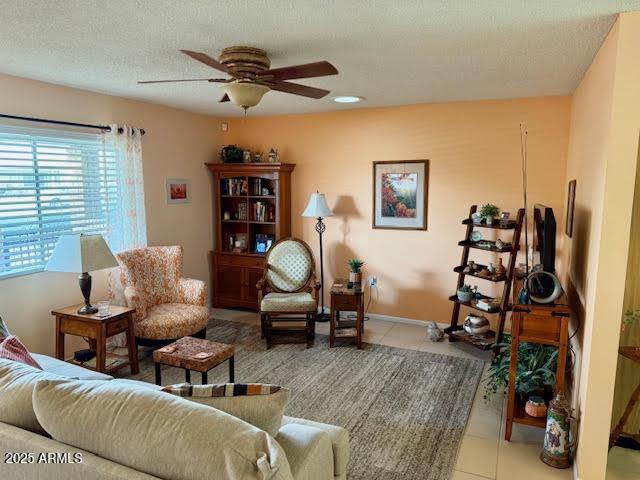 living area featuring a textured ceiling, a ceiling fan, and tile patterned floors