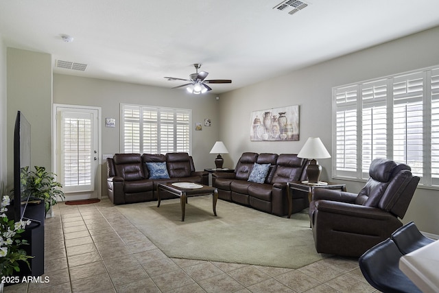 carpeted living area with visible vents, ceiling fan, and tile patterned floors