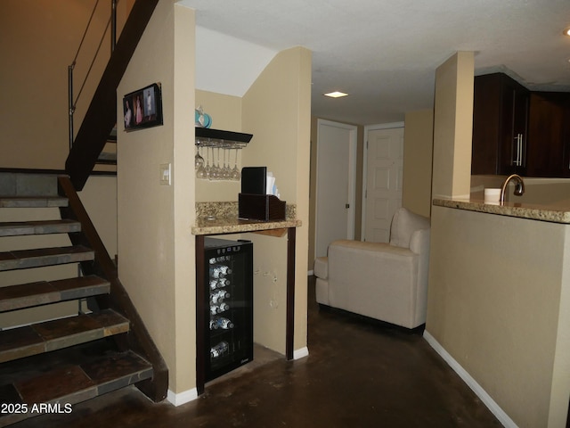 stairs featuring wet bar, concrete flooring, and beverage cooler