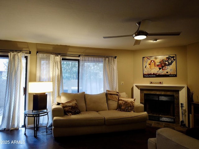 living room featuring ceiling fan, plenty of natural light, and a tiled fireplace