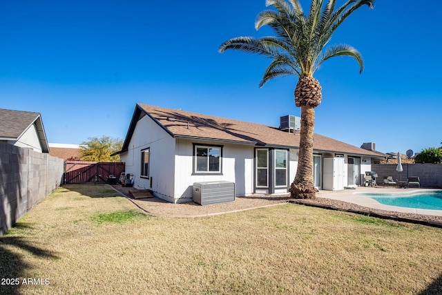 back of property with a fenced in pool, a lawn, and central air condition unit