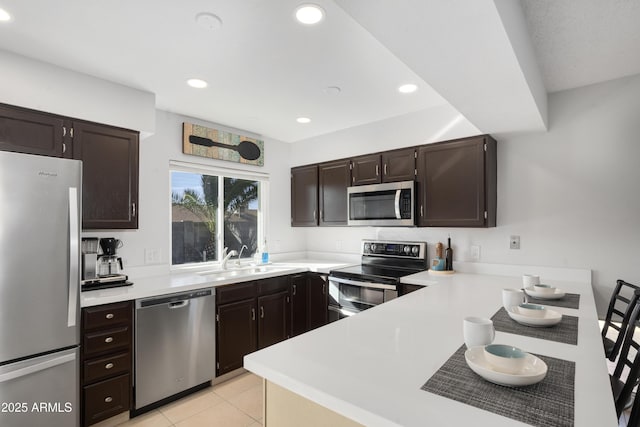 kitchen featuring appliances with stainless steel finishes, kitchen peninsula, sink, and light tile patterned floors