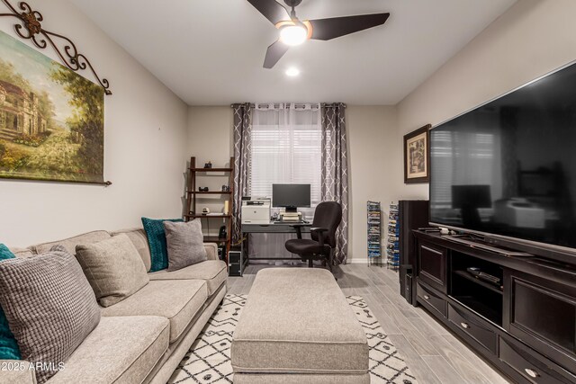living area with light wood-style floors, baseboards, and ceiling fan