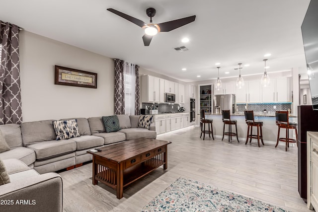 living room featuring visible vents, a ceiling fan, light wood-style floors, and recessed lighting