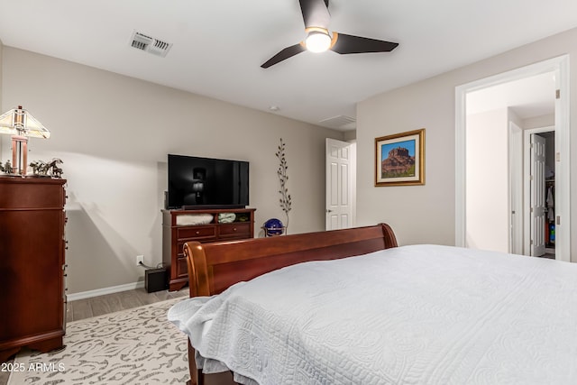 bedroom with visible vents, a ceiling fan, baseboards, and wood finished floors