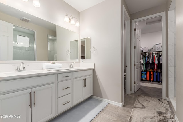 full bathroom featuring double vanity, a sink, wood finished floors, and a stall shower