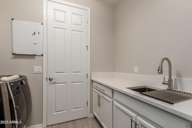 laundry area featuring a sink, light wood-style flooring, washer / dryer, and cabinet space