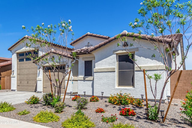 mediterranean / spanish-style house with a tiled roof, a garage, fence, concrete driveway, and stucco siding