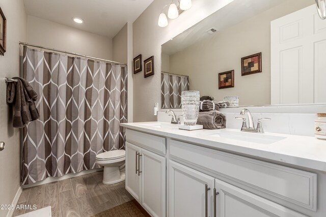bathroom featuring visible vents, a sink, double vanity, and toilet