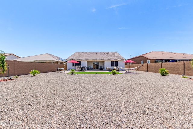 back of property with a fenced backyard, stucco siding, and a patio area