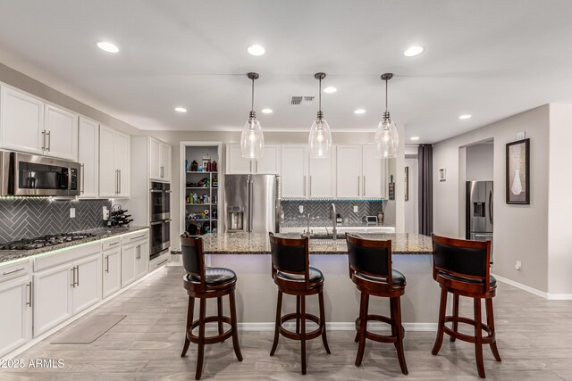 kitchen with light wood-type flooring, decorative backsplash, and stainless steel appliances