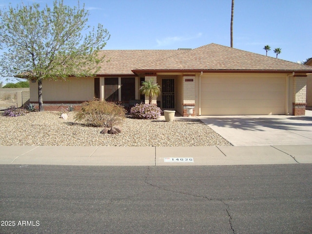 single story home featuring driveway, a shingled roof, an attached garage, and brick siding