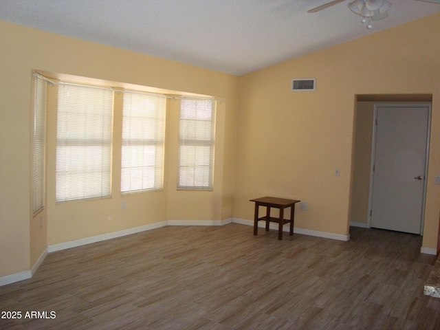 unfurnished room featuring visible vents, ceiling fan, vaulted ceiling, wood finished floors, and baseboards