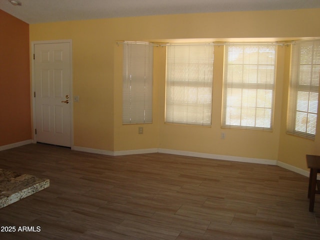 unfurnished room with baseboards and wood finished floors