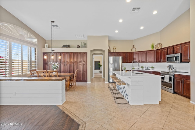 2239 N Calvin, Mesa, AZ 85207 - kitchen with stainless steel appliances, a sink, a kitchen breakfast bar, arched walkways, and backsplash