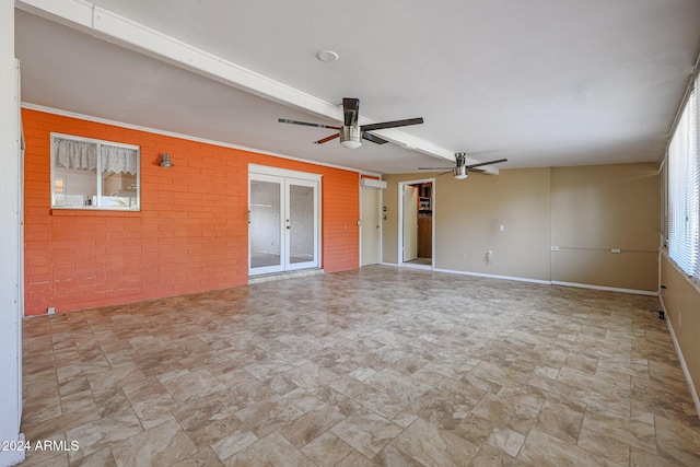 spare room with ceiling fan and brick wall