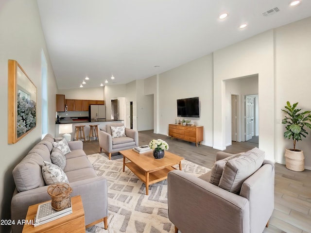 living room with light hardwood / wood-style floors and high vaulted ceiling