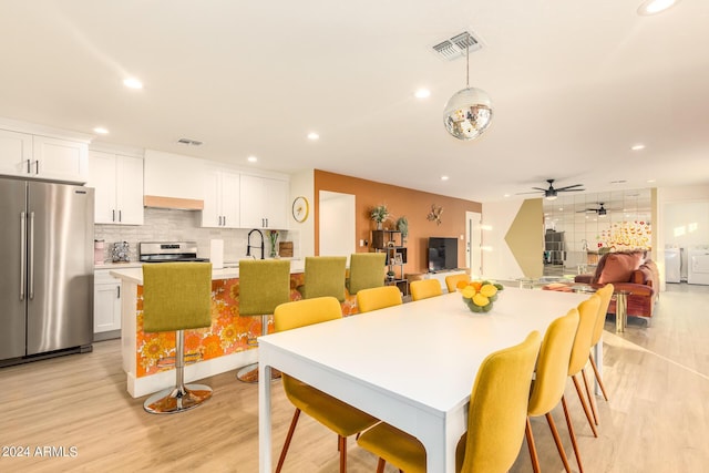 dining room with ceiling fan, washer and clothes dryer, and light wood-type flooring