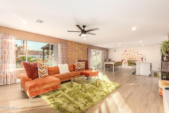 living room with ceiling fan, sink, and light hardwood / wood-style floors