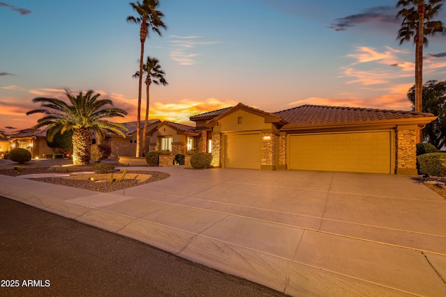 view of front facade featuring stone siding, driveway, a tiled roof, and an attached garage