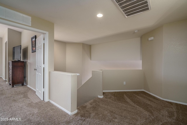 hallway with an upstairs landing, visible vents, and carpet floors