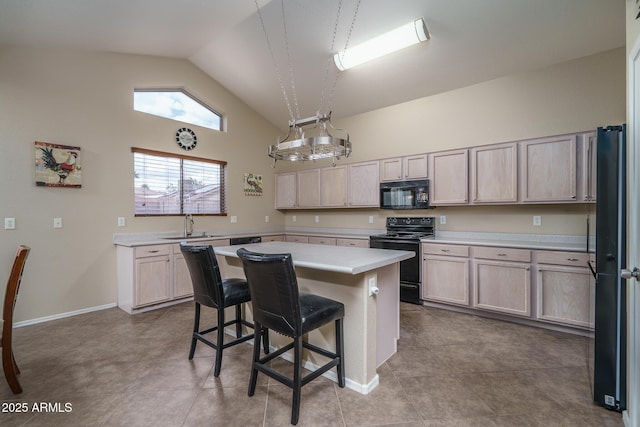 kitchen featuring black appliances, a sink, a kitchen breakfast bar, a center island, and light countertops