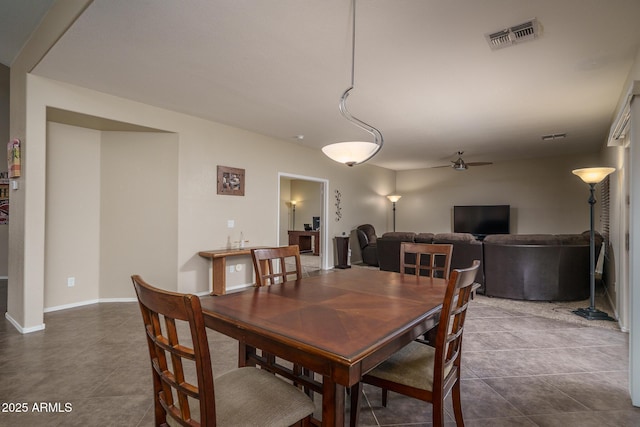 dining area with dark tile patterned floors, visible vents, baseboards, and ceiling fan