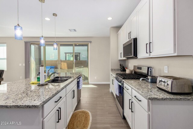 kitchen with sink, white cabinetry, stainless steel appliances, a healthy amount of sunlight, and decorative light fixtures