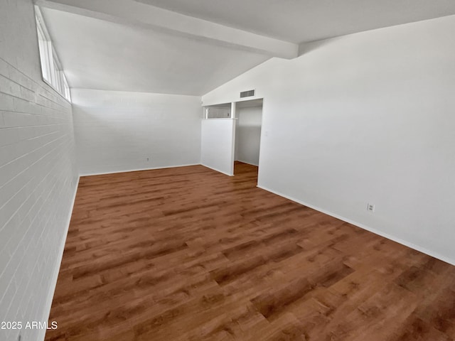 unfurnished room with dark wood-type flooring and vaulted ceiling with beams