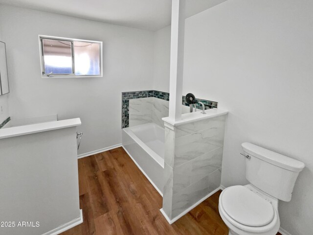 bathroom with hardwood / wood-style floors, vanity, a bath, and toilet