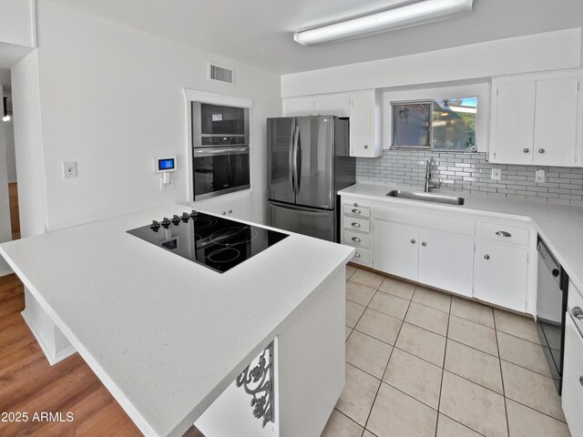 kitchen featuring white cabinetry, sink, decorative backsplash, and black appliances